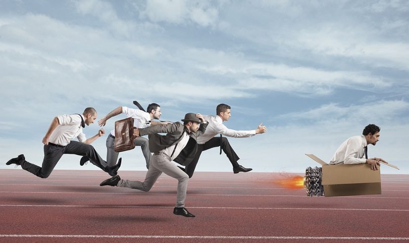 Image of funny looking sales men on a running track chasing a leader in a rocket style cardboard box